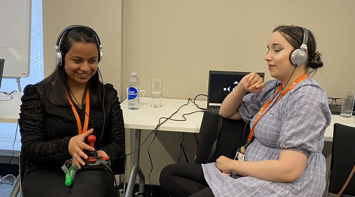 Nadia Patel plays the audio game with a joystick controller, while Fatima Rifai, both of Galloway's Society for the Blind, listens in, via headphones.
