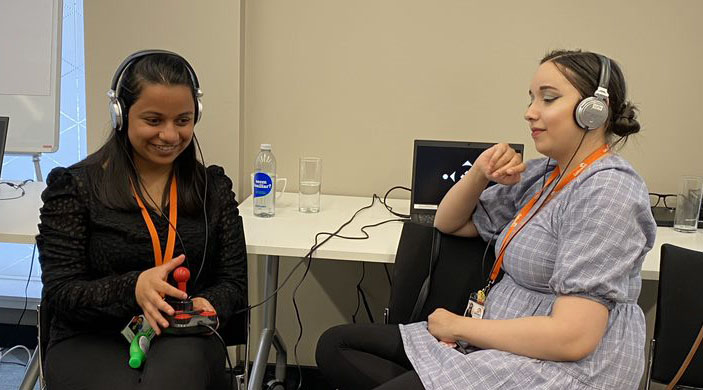 Nadia Patel plays the audio game with a joystick controller, while Fatima Rifai, both of Galloway's Society for the Blind, listens in, via headphones. 
