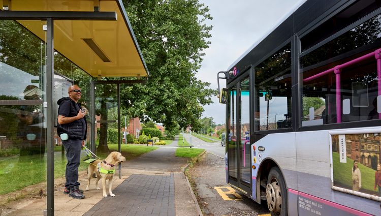 Blind person with guide dog at bus stop